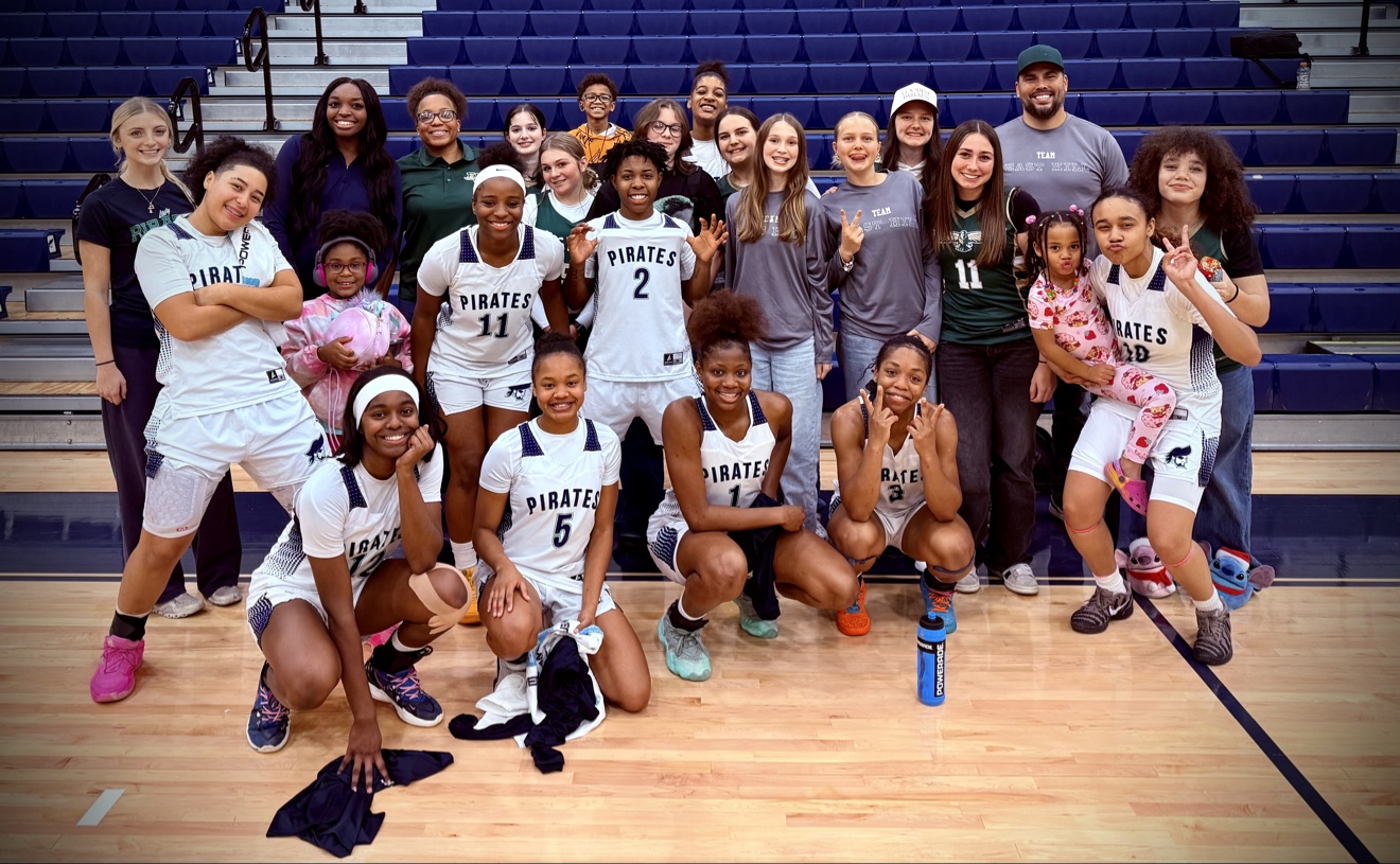 Coach J on the court with her Pirates girls basketball team and families after a game
